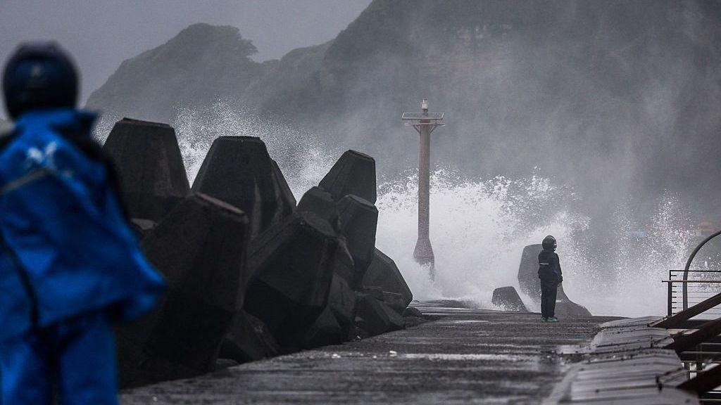Large waves crash against a coastal breakwater during stormy weather