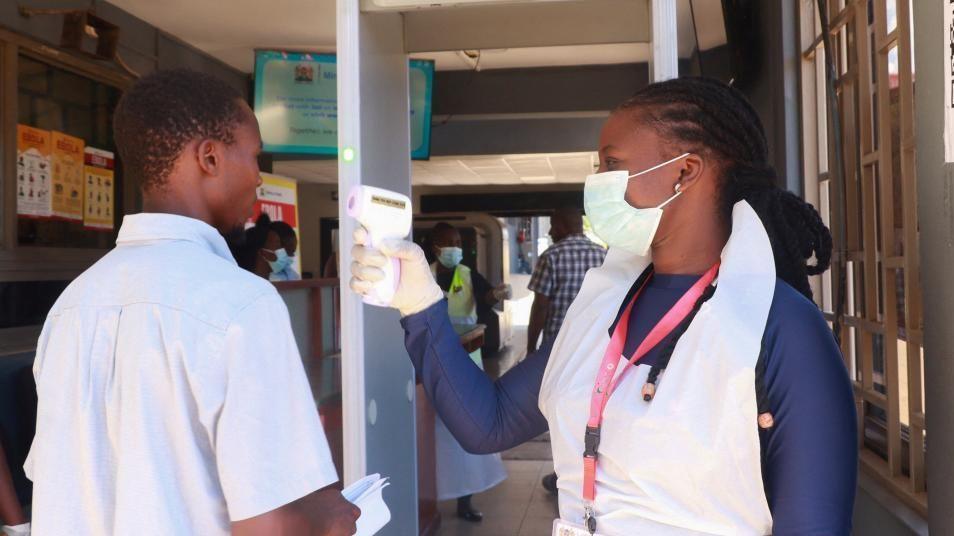 Medical worker checks a traveler’s temperature at Kenya-Uganda border