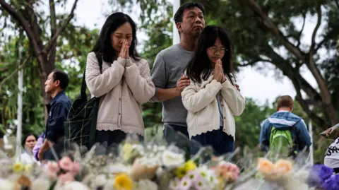 Reflecting Tragedy: Hong Kong Fire Claims 146 Lives as Thousands Mourn